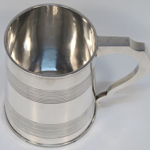 A very handsome Antique Georgian Sterling Silver pint tankard or mug, having a plain round straight-sided body with two bands of hand-chased reeded decoration and applied reeded borders, a square cross-section scroll handle, and sitting on a flat base. This elegant silver pint mug was made by Rebecca Emes and Edward Barnard I of London in 1810. The dimensions of this fine hand-made antique silver mug or tankard are height 11 cms (4.3 inches), length 13.5 cms (5.25 inches), and it weighs approx. 349g (11.25 troy ounces).   