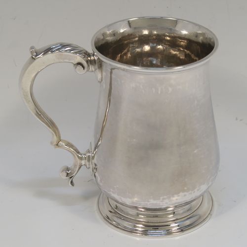 A very handsome Antique Georgian George III Sterling Silver half-pint tankard, having a plain round bellied body, a scroll handle with Anthemion leaf thumb-piece, and sitting on a pedestal foot. This elegant silver half-pint mug was made by Thomas Wallis I of London in 1779. The dimensions of this fine hand-made antique silver half-pint mug or tankard are height 10 cms (4 inches), diameter at top 7 cms (2.75 inches), and it weighs approx. 199g (6.4 troy ounces).   