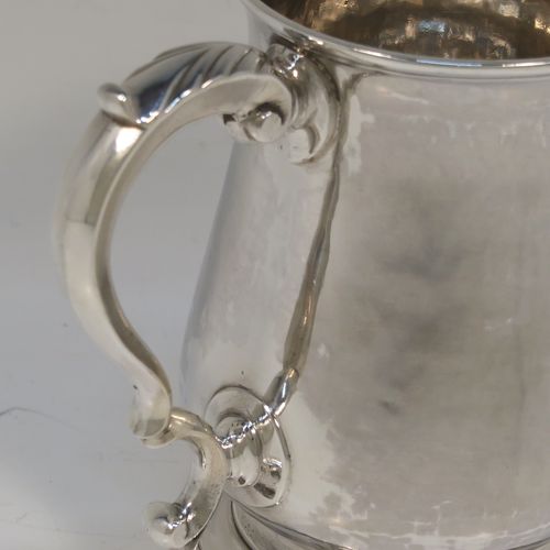 A very handsome Antique Georgian George III Sterling Silver half-pint tankard, having a plain round bellied body, a scroll handle with Anthemion leaf thumb-piece, and sitting on a pedestal foot. This elegant silver half-pint mug was made by Thomas Wallis I of London in 1779. The dimensions of this fine hand-made antique silver half-pint mug or tankard are height 10 cms (4 inches), diameter at top 7 cms (2.75 inches), and it weighs approx. 199g (6.4 troy ounces).   