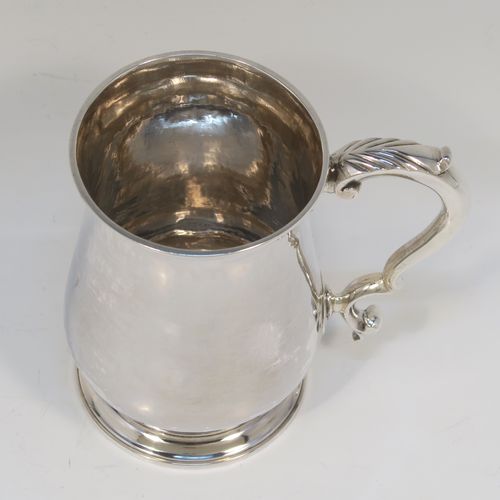 A very handsome Antique Georgian George III Sterling Silver half-pint tankard, having a plain round bellied body, a scroll handle with Anthemion leaf thumb-piece, and sitting on a pedestal foot. This elegant silver half-pint mug was made by Thomas Wallis I of London in 1779. The dimensions of this fine hand-made antique silver half-pint mug or tankard are height 10 cms (4 inches), diameter at top 7 cms (2.75 inches), and it weighs approx. 199g (6.4 troy ounces).   