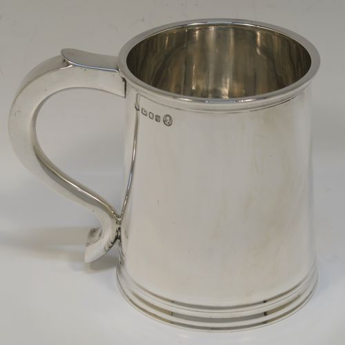 A very handsome George I style Sterling Silver pint tankard, having a plain round straight-sided body with tapering sides, a scroll side-handle, with applied reeded borders top and bottom, and all sitting on a collet foot. This elegant silver pint mug was made by Robert Comyns of London in 1953. The dimensions of this fine hand-made silver tankard are height 11 cms (4.3 inches), diameter at top 8.5 cms (3.3 inches), and it weighs approx. 270g (8.7 troy ounces).  