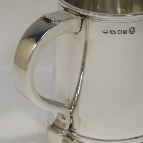 A very handsome George I style Sterling Silver pint tankard, having a plain round straight-sided body with tapering sides, a scroll side-handle, with applied reeded borders top and bottom, and all sitting on a collet foot. This elegant silver pint mug was made by Robert Comyns of London in 1953. The dimensions of this fine hand-made silver tankard are height 11 cms (4.3 inches), diameter at top 8.5 cms (3.3 inches), and it weighs approx. 270g (8.7 troy ounces).  