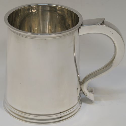 A very handsome George I style Sterling Silver pint tankard, having a plain round straight-sided body with tapering sides, a scroll side-handle, with applied reeded borders top and bottom, and all sitting on a collet foot. This elegant silver pint mug was made by Robert Comyns of London in 1953. The dimensions of this fine hand-made silver tankard are height 11 cms (4.3 inches), diameter at top 8.5 cms (3.3 inches), and it weighs approx. 270g (8.7 troy ounces).  