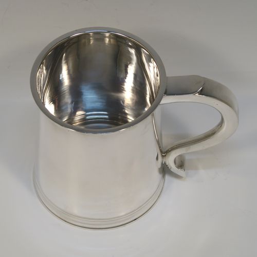 A very handsome George I style Sterling Silver pint tankard, having a plain round straight-sided body with tapering sides, a scroll side-handle, with applied reeded borders top and bottom, and all sitting on a collet foot. This elegant silver pint mug was made by Robert Comyns of London in 1953. The dimensions of this fine hand-made silver tankard are height 11 cms (4.3 inches), diameter at top 8.5 cms (3.3 inches), and it weighs approx. 270g (8.7 troy ounces).  