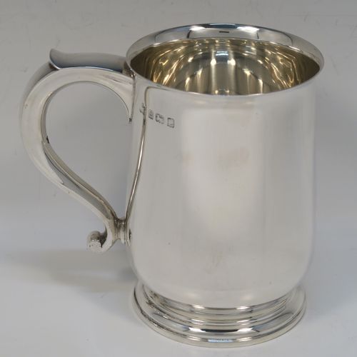 A very handsome Sterling Silver pint tankard or mug, having a plain round body with straight sides and a tucked under belly, a scroll side-handle, and sitting on a pedestal foot. This elegant silver pint mug was made by Elkington and Co., of Birmingham in 1935. The dimensions of this fine hand-made silver pint mug or tankard are height 12.5 cms (5 inches), diameter at top 8.5 cms (3.3 inches), and it weighs approx. 384g (12.4 troy ounces).   