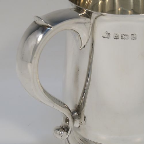 A very handsome Sterling Silver pint tankard or mug, having a plain round body with straight sides and a tucked under belly, a scroll side-handle, and sitting on a pedestal foot. This elegant silver pint mug was made by Elkington and Co., of Birmingham in 1935. The dimensions of this fine hand-made silver pint mug or tankard are height 12.5 cms (5 inches), diameter at top 8.5 cms (3.3 inches), and it weighs approx. 384g (12.4 troy ounces).   