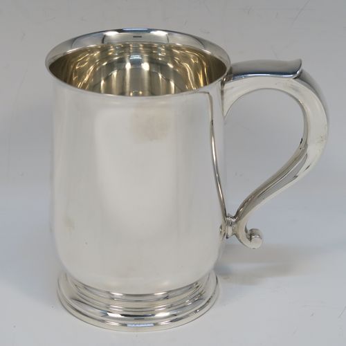 A very handsome Sterling Silver pint tankard or mug, having a plain round body with straight sides and a tucked under belly, a scroll side-handle, and sitting on a pedestal foot. This elegant silver pint mug was made by Elkington and Co., of Birmingham in 1935. The dimensions of this fine hand-made silver pint mug or tankard are height 12.5 cms (5 inches), diameter at top 8.5 cms (3.3 inches), and it weighs approx. 384g (12.4 troy ounces).   