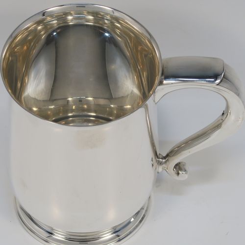 A very handsome Sterling Silver pint tankard or mug, having a plain round body with straight sides and a tucked under belly, a scroll side-handle, and sitting on a pedestal foot. This elegant silver pint mug was made by Elkington and Co., of Birmingham in 1935. The dimensions of this fine hand-made silver pint mug or tankard are height 12.5 cms (5 inches), diameter at top 8.5 cms (3.3 inches), and it weighs approx. 384g (12.4 troy ounces).   