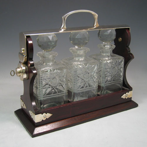    Antique Edwardian silver plated and wood-framed three bottle tantalus with hand-cut crystal decanters made in ca. 1910. Height 30 cms, width 35 cms.