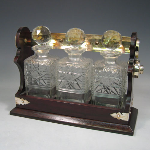    Antique Edwardian silver plated and wood-framed three bottle tantalus with hand-cut crystal decanters made in ca. 1910. Height 30 cms, width 35 cms.