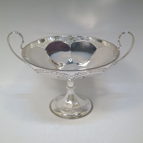 A very pretty Sterling Silver tazza dish, having a round body with an applied gadroon border above a lobed band of hand-pierced floral decoration, with two scroll side-handles, and all sitting on a matching pedestal foot. Made by Elkington and Co., of Birmingham in 1920. The dimensions of this fine hand-made silver tazza dish are height 18.5 cms (7.3 inches), diameter 21 cms (8.25 inches), and it weighs approx. 615g (19.8 troy ounces).   