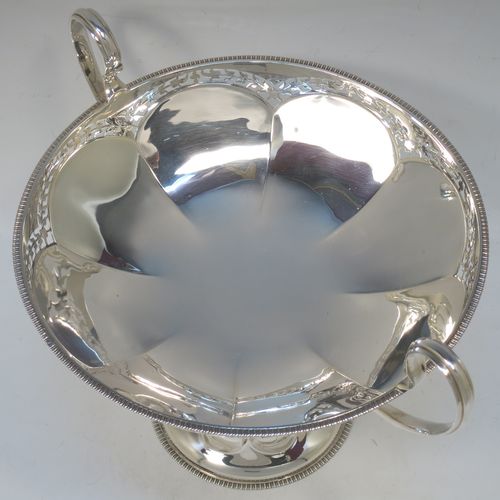 A very pretty Sterling Silver tazza dish, having a round body with an applied gadroon border above a lobed band of hand-pierced floral decoration, with two scroll side-handles, and all sitting on a matching pedestal foot. Made by Elkington and Co., of Birmingham in 1920. The dimensions of this fine hand-made silver tazza dish are height 18.5 cms (7.3 inches), diameter 21 cms (8.25 inches), and it weighs approx. 615g (19.8 troy ounces).   