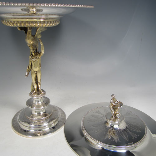 Antique Victorian sterling silver tazza dish and cover, having a round body with half-fluted chasing and an applied gadroon border, held up by a cast gold-gilt model of Zeus with his emblem of an eagle, and sitting on a pedestal foot with hand-engraved floral decoration, together with a lift off lid with a cast model of Veritas and Globe as a finial. Made by Alexander Macrae of London in 1868. The dimensions of this fine hand-made silver tazza dish are height 42 cms (16.5 inches), diameter 28 cms (11 inches), and it weighs approx. 1,954g (63 troy ounces).