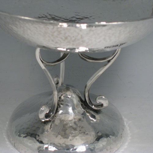    Antique Edwardian sterling silver Arts and Crafts tazza dish, having a round bowl sitting on a pedestal foot with scroll work, and an all-over hand-hammered plenished finish. Made by Walker and Hall of Sheffield in 1909. Height 15 cms (6 inches), diameter 20 cms (8 inches). Weight approx. 405g (13 troy ounces).