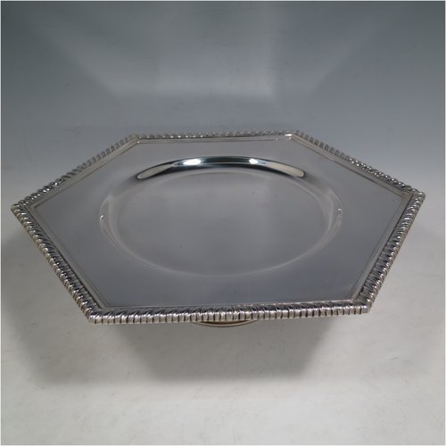 An Antique Sterling Silver very heavy tazza cake dish, having a plain hexagonal body, with a gadroon border, and sitting on a pedestal foot with applied cut-card work and hand-chased fluting. Made by Sebastian Garrard of London in 1911. The dimensions of this fine hand-made antique silver tazza dish are height 8 cms (3 inches), width of plate 31 cms (12.25 inches), and the weight is approx. 1,425g (46 troy ounces).   