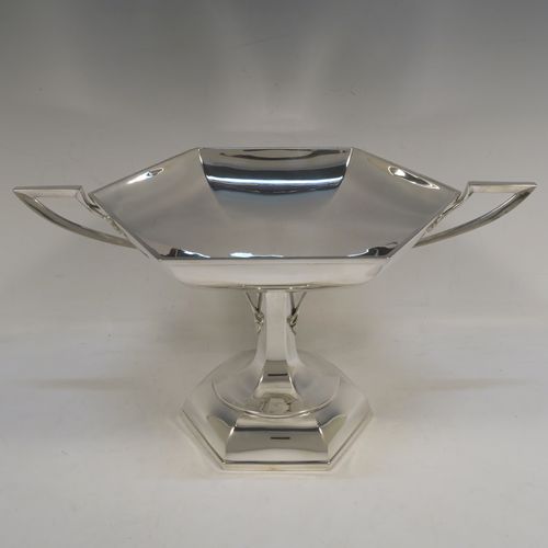 A very handsome Sterling Silver tazza dish or bowl, having a plain hexagonal paneled body, with two cast side-handles having scroll-leaf terminals, and sitting on a matching pedestal foot. This beautiful tazza dish was made by Walker and Hall of Sheffield in 1927. The dimensions of this fine hand-made silver tazza bowl or dish are height 16 cms (6.3 inches), width across handles 31 cms (12.25 inches), and it weighs approx. 638g (20.6 troy ounces).   