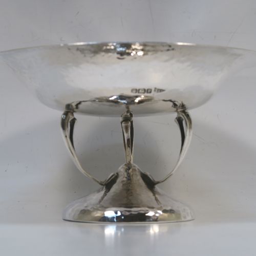 A very handsome Antique Edwardian Sterling Silver Arts and Crafts style tazza dish, having a round bowl attached to a pedestal foot with three scroll arms, and an all-over hand-hammered or plenished finish. This beautiful silver tazza dish was made by Walker and Hall of Sheffield in 1909. The dimensions of this fine hand-made antique silver dish are height 9 cms (3.5 inches), diameter 16 cms (6.3 inches), and it weighs approx. 203g (6.5 troy ounces).   