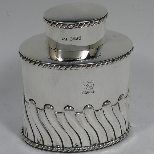 A very handsome Antique Victorian sterling silver tea caddy box, having an oval straight-sided body with hand-chased swirl-fluted decoration, applied gadroon borders, and a pull-off lid which was used as a measure, all sitting on a flat base. Made by Henry Atkins of Sheffield in 1895. The dimensions of this fine antique silver tea caddy box are height 9 cms (3.5 inches), length 8 cms (3 inches), width 5.5 cms (2.25 inches), and it weighs approx. 146g (4.7 troy ounces). Please note that this item has a part-crest on the main body.