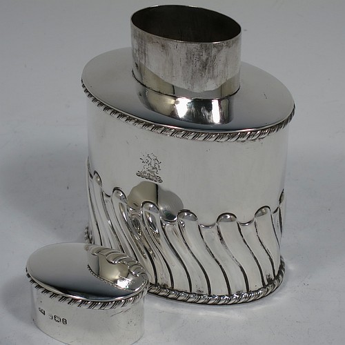 A very handsome Antique Victorian sterling silver tea caddy box, having an oval straight-sided body with hand-chased swirl-fluted decoration, applied gadroon borders, and a pull-off lid which was used as a measure, all sitting on a flat base. Made by Henry Atkins of Sheffield in 1895. The dimensions of this fine antique silver tea caddy box are height 9 cms (3.5 inches), length 8 cms (3 inches), width 5.5 cms (2.25 inches), and it weighs approx. 146g (4.7 troy ounces). Please note that this item has a part-crest on the main body.