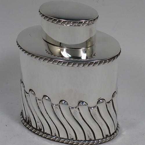 A very handsome Antique Victorian sterling silver tea caddy box, having an oval straight-sided body with hand-chased swirl-fluted decoration, applied gadroon borders, and a pull-off lid which was used as a measure, all sitting on a flat base. Made by Henry Atkins of Sheffield in 1895. The dimensions of this fine antique silver tea caddy box are height 9 cms (3.5 inches), length 8 cms (3 inches), width 5.5 cms (2.25 inches), and it weighs approx. 146g (4.7 troy ounces). Please note that this item has a part-crest on the main body.