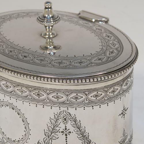 A very pretty Antique Victorian Sterling Silver tea caddy box, having an oval straight-sided body with applied bead borders, a cast urn-shaped finial sitting on a flat hinged lid, with hand-engraved bands top and bottom, together with neoclassical style engraved swags surrounding round vacant cartouches on either side, and all sitting on a flat base. This beautiful antique silver tea caddy box was made by Henry Wilkinson and Co., of London in 1875. The dimensions of this fine hand-made antique silver tea caddy box are height 11 cms (4.3 inches), length 13 cms (5 inches), depth 10 cms (4 inches), and it weighs approx. 407g (13 troy ounces).  