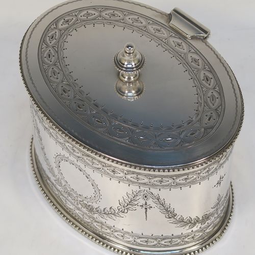 A very pretty Antique Victorian Sterling Silver tea caddy box, having an oval straight-sided body with applied bead borders, a cast urn-shaped finial sitting on a flat hinged lid, with hand-engraved bands top and bottom, together with neoclassical style engraved swags surrounding round vacant cartouches on either side, and all sitting on a flat base. This beautiful antique silver tea caddy box was made by Henry Wilkinson and Co., of London in 1875. The dimensions of this fine hand-made antique silver tea caddy box are height 11 cms (4.3 inches), length 13 cms (5 inches), depth 10 cms (4 inches), and it weighs approx. 407g (13 troy ounces).  