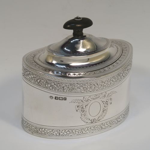 A very pretty Antique Edwardian Sterling Silver tea caddy box, having an oval straight-sided body, a wooden finial sitting on an oval domed and hinged lid, all with hand-engraved bands of floral decoration, together with floral engraving surrounding oval vacant cartouches on either side, and all sitting on a flat base. This beautiful antique silver tea caddy box was made by William Hutton and Sons of Sheffield in 1902. The dimensions of this fine hand-made antique silver tea caddy box are height 9.5 cms (3.75 inches), length 11 cms (4.25 inches), depth 7.5 cms (3 inches), and it weighs approx. 230g (7.4 troy ounces).   