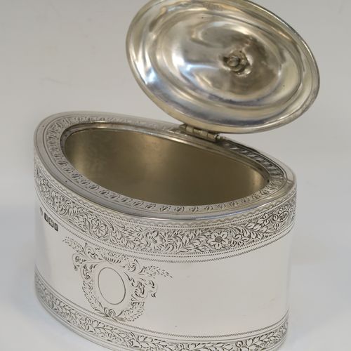 A very pretty Antique Edwardian Sterling Silver tea caddy box, having an oval straight-sided body, a wooden finial sitting on an oval domed and hinged lid, all with hand-engraved bands of floral decoration, together with floral engraving surrounding oval vacant cartouches on either side, and all sitting on a flat base. This beautiful antique silver tea caddy box was made by William Hutton and Sons of Sheffield in 1902. The dimensions of this fine hand-made antique silver tea caddy box are height 9.5 cms (3.75 inches), length 11 cms (4.25 inches), depth 7.5 cms (3 inches), and it weighs approx. 230g (7.4 troy ounces).   