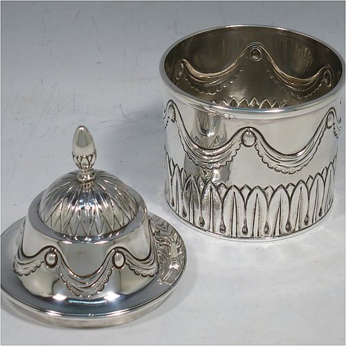 An Antique Georgian Sterling Silver tea caddy box, having a round straight-sided body with hand-chased Neoclassical style swags and anthemion leaves, with applied reeded borders, a pull-off domed lid with cast acorn finial, and all sitting on a flat base. Made by the Lias Brothers of London in 1826. The dimensions of this fine antique silver tea caddy box are height 12 cms (4.75 inches), diameter 7 cms (2.75 inches), and it weighs approx. 190g (6 troy ounces).    