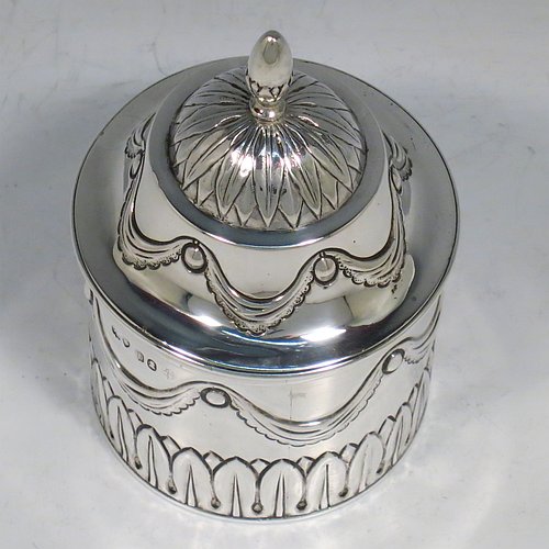 An Antique Georgian Sterling Silver tea caddy box, having a round straight-sided body with hand-chased Neoclassical style swags and anthemion leaves, with applied reeded borders, a pull-off domed lid with cast acorn finial, and all sitting on a flat base. Made by the Lias Brothers of London in 1826. The dimensions of this fine antique silver tea caddy box are height 12 cms (4.75 inches), diameter 7 cms (2.75 inches), and it weighs approx. 190g (6 troy ounces).    