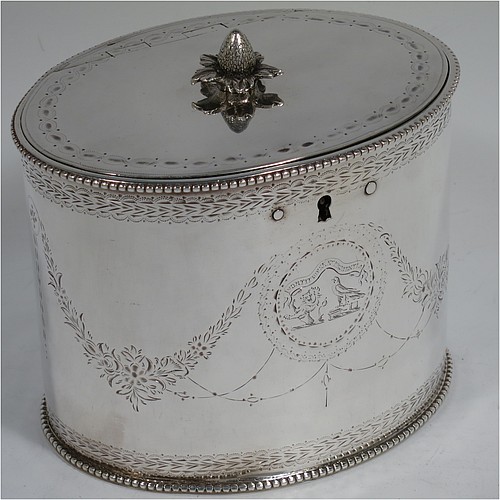 A very handsome Antique Georgian Sterling Silver tea caddy box, having an oval straight-sided body with applied bead borders, a cast floral finial sitting on a lid with flat hidden hinge, with hand-engraved bands top and bottom, together with neoclassical style engraved swags, and original lock with key. Made by Samuel Wood of London in 1779. The dimensions of this fine hand-made antique tea caddy box are height 10 cms (4 inches), length 12 cms (4.75 inches), width 9 cms (3.5 inches), and it weighs approx. 385g (12.4 troy ounces).