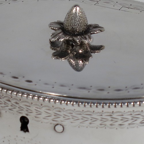 A very handsome Antique Georgian Sterling Silver tea caddy box, having an oval straight-sided body with applied bead borders, a cast floral finial sitting on a lid with flat hidden hinge, with hand-engraved bands top and bottom, together with neoclassical style engraved swags, and original lock with key. Made by Samuel Wood of London in 1779. The dimensions of this fine hand-made antique tea caddy box are height 10 cms (4 inches), length 12 cms (4.75 inches), width 9 cms (3.5 inches), and it weighs approx. 385g (12.4 troy ounces).