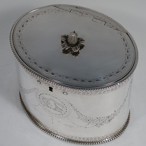 A very handsome Antique Georgian Sterling Silver tea caddy box, having an oval straight-sided body with applied bead borders, a cast floral finial sitting on a lid with flat hidden hinge, with hand-engraved bands top and bottom, together with neoclassical style engraved swags, and original lock with key. Made by Samuel Wood of London in 1779. The dimensions of this fine hand-made antique tea caddy box are height 10 cms (4 inches), length 12 cms (4.75 inches), width 9 cms (3.5 inches), and it weighs approx. 385g (12.4 troy ounces).