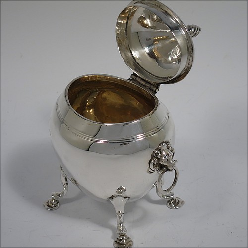 An Antique Edwardian Sterling Silver tea caddy box, having a plain oval bellied body with an upper band of hand-chased reeded decoration, a hinged lid with a cast swirl finial, with two cast lions-head ring side-handles, a gold-gilt interior, and sitting on four cast hoof feet with trefoil shoulders. Made by Nathan and Hayes of Chester in 1906. The dimensions of this fine hand-made antique silver tea caddy box are height 11.5 cms (4.5 inches), width 9 cms (3.5 inches), depth 6.5 cms (2.5 inches), and it weighs approx. 167g (5.4 troy ounces).    