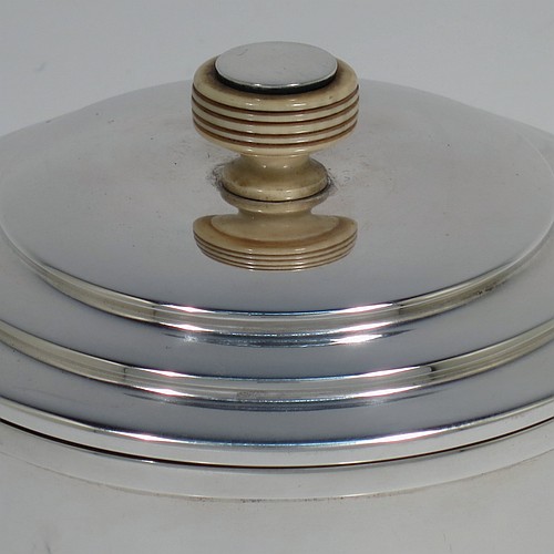 A very handsome Art Deco style Sterling silver tea caddy box, having a plain cylindrical body with straight sides and applied reeded borders, a lift-off lid with stepped decoration and a bone finial, and sitting on a collet foot. Made by Hukin and Heath of Birmingham in 1945. The dimensions of this fine hand-made Art Deco silver tea caddy box are height 10 cms (4 inches), diameter 9 cms (3.5 inches), and it weighs approx. 246g (7.9 troy ounces).    