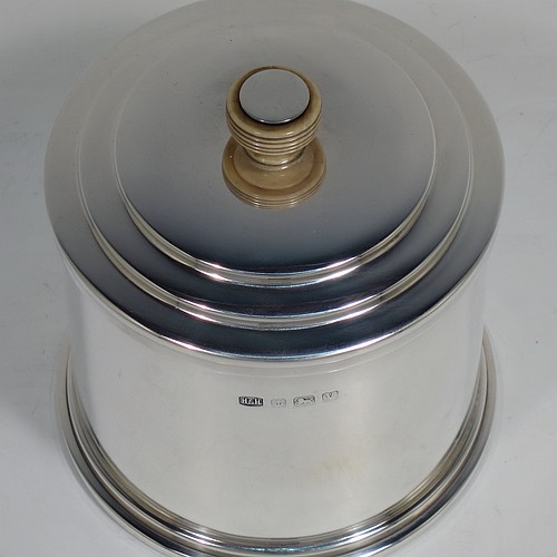 A very handsome Art Deco style Sterling silver tea caddy box, having a plain cylindrical body with straight sides and applied reeded borders, a lift-off lid with stepped decoration and a bone finial, and sitting on a collet foot. Made by Hukin and Heath of Birmingham in 1945. The dimensions of this fine hand-made Art Deco silver tea caddy box are height 10 cms (4 inches), diameter 9 cms (3.5 inches), and it weighs approx. 246g (7.9 troy ounces).    