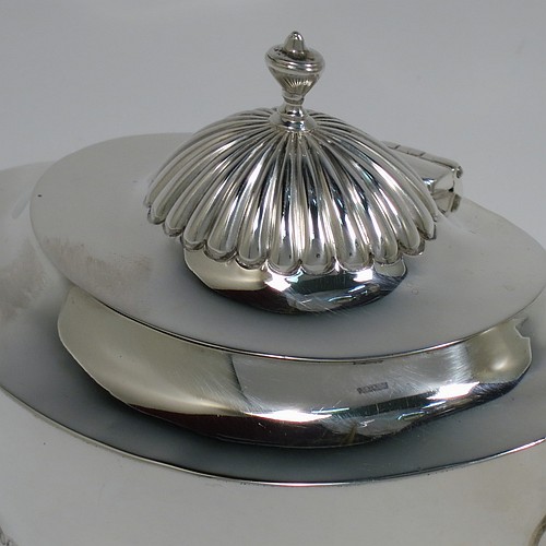 An Antique Edwardian Sterling Silver tea caddy box, having an oval bellied body with hand-chased half-fluted decoration, two lion-mask and ring side-handles, a hinged domed lid with matching fluting and a cast urn finial, and all sitting on a collet foot. Made by Goldsmiths and Silversmiths of London in 1906. The dimensions of this fine hand-made antique silver tea caddy box are height 11 cms (4.25 inches), length 12.5 cms (5 inches), width 8 cms (3.25 inches), and it weighs approx. 198g (6.4 troy ounces).   