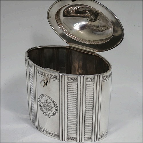 A very handsome Antique Georgian Sterling Silver tea caddy box, having an oval straight-sided body with hand-engraved panels between hand-chased vertical bands of fluting, with hand-engraved laurel-leaf cartouches on either side, a fluted and domed lid with flat invisible hinge and pineapple finial, all sitting on a flat base and with its original lock and key. Made by Henry Chawner of London in 1795. The dimensions of this fine hand-made antique silver tea caddy box are height 16 cms (6.25 inches), length 14 cms (5.5 inches), width 9.5 cms (3.75 inches), and it weighs approx. 333g (10.7 troy ounces).   