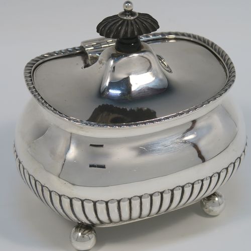 An elegant Antique Edwardian Sterling Silver tea caddy box, having a rectangular bellied body with hand-chased half-fluted decoration, an applied gadroon top border, a hinged domed lid with a black stained wooden finial, and all sitting on four ball feet. This handsome silver tea caddy box was made by Henry Stratford of London in 1902. The dimensions of this fine hand-made antique silver tea caddy box are height 11.5 cms (4.5 inches), length 11.5 cms (4.5 inches), width 9 cms (3.5 inches), and it weighs approx. 230g (7.4 troy ounces).  