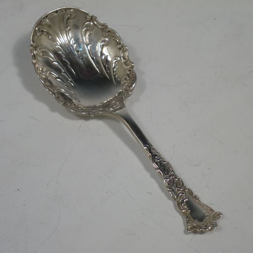 An Antique Sterling Silver tea caddy spoon, with a floral patterned handle, and a hand-chased oval bowl with scroll decoration. Made by Joseph Gloster of Birmingham in 1911. The dimensions of this fine hand-made antique silver tea caddy spoon are length 10 cms (4 inches), width across bowl 3.5 cms (1.3 inches), and it weighs approx. 18g (0.6 troy ounces).    