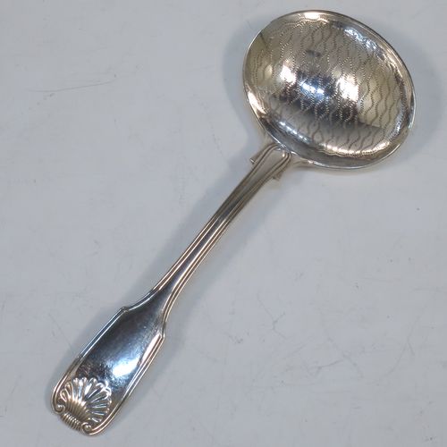 An Antique Georgian Sterling Silver tea caddy spoon, having a double-struck Fiddle, Thread, and Shell pattern handle, and a hand-engraved oval bowl with wriggle-work decoration. Made in ca. 1820 (marks rubbed). The dimensions of this fine hand-made antique silver tea caddy spoon are length 12 cms (4.75 inches), width across bowl 4.5 cms (1.75 inches), and it weighs approx. 27g (0.9 troy ounces).  