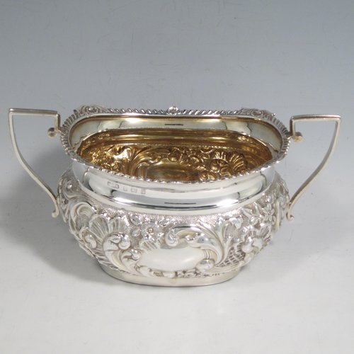 Antique Edwardian sterling silver four-piece tea and coffee set, having rectangular baluster bodies with rounded corners, with hand-chased floral decoration, and wooden handles and finials, the sugar bowl and cream jug with gold-gilt interiors, and all sitting on flat bases. Made by W. G. Knight of Birmingham in 1909. The dimensions of this fine hand-made silver tea and coffee service are length of teapot 32 cms (12.5 inches), height of hot-water pot 23 cms (9 inches), and the total weight is approx. 1,640g (53 troy ounces).   