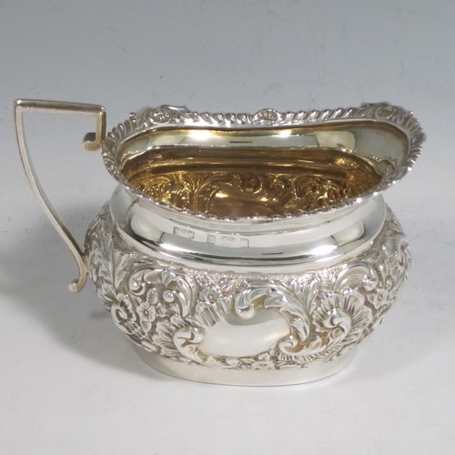 Antique Edwardian sterling silver four-piece tea and coffee set, having rectangular baluster bodies with rounded corners, with hand-chased floral decoration, and wooden handles and finials, the sugar bowl and cream jug with gold-gilt interiors, and all sitting on flat bases. Made by W. G. Knight of Birmingham in 1909. The dimensions of this fine hand-made silver tea and coffee service are length of teapot 32 cms (12.5 inches), height of hot-water pot 23 cms (9 inches), and the total weight is approx. 1,640g (53 troy ounces).   