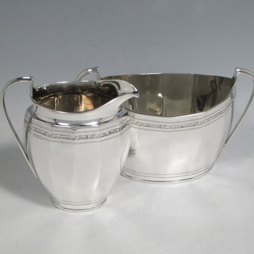 Sterling silver Georgian style five-piece tea and coffee service, consisting of teapot, coffee pot, hot water pot, sugar bowl and cream jug. Having oval panelled bodies with a band of floral decoration, with wooden handles and ivory pineapple shaped finials, and sitting on flat bases. Made by Roberts & Belk of Sheffield in 1919. The dimensions of this fine hand-made tea and coffee service are length of teapot 27 cms (10.5 inches), height of coffee pot 22 cms (8.75 inches), and the total weight is approx. 1,800g (58 troy ounces).