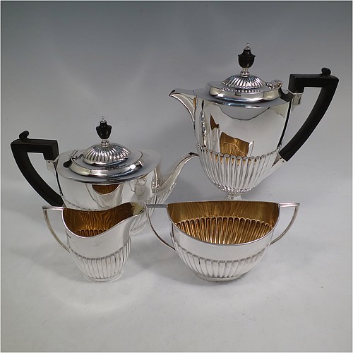 A very handsome Antique Edwardian Sterling Silver Queen Anne style four-piece tea and coffee set consisting of a coffee pot, tea-pot, sugar bowl, and milk / cream jug, having oval bodies with hand-chased half-fluted decoration, with wooden handles and finials, and all sitting on pedestal and collet feet. All made by Roberts and Belk of Sheffield in 1907/10. The dimensions of this fine hand-made antique silver tea and coffee service are length of teapot 26.5 cms (10.5 inches), height of coffee pot 26 cms (10.25 inches), and the total weight is approx. 1,350g (42 troy ounces).   