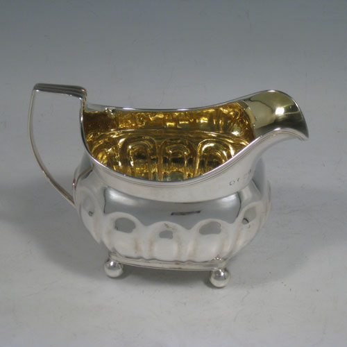 Antique Georgian sterling silver four-piece tea and coffee service, consisting of a coffee pot, tea pot, sugar bowl, and cream jug, having melon fluted bodies, gold gilt interiors, hinged lids with wooden finials, and insulated wooden handles, all sitting on four ball feet. Made by Henry Nutting and Robert Hennell II of London in 1808. Height of coffee pot 21.5 cms (8.5 inches), length of teapot 27 cms (10.5 inches). Total weight approx. 1,800g (58 troy ounces). Please note that all items are part-crested.