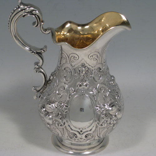 Antique Victorian sterling silver four-piece tea and coffee service, having round hand-chased bodies with floral decoration, hinged lids and finials, insulated handles, and gold-gilt interiors. Made by Robert Hennell of London in 1858/59. Height of coffee pot 25.5 cms (10 inches), length of teapot 25.5 cms (10 inches). Total weight approx. 2,340g (75.5 troy ounces).