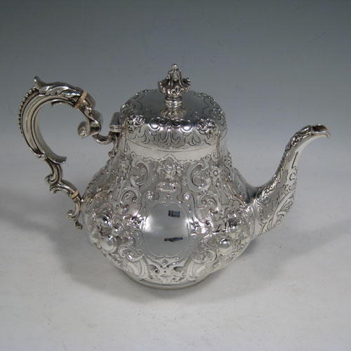 Antique Victorian sterling silver four-piece tea and coffee service, having round hand-chased bodies with floral decoration, hinged lids and finials, insulated handles, and gold-gilt interiors. Made by Robert Hennell of London in 1858/59. Height of coffee pot 25.5 cms (10 inches), length of teapot 25.5 cms (10 inches). Total weight approx. 2,340g (75.5 troy ounces).