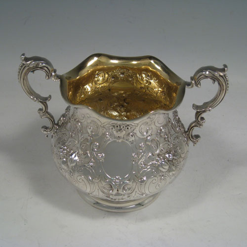 Antique Victorian sterling silver four-piece tea and coffee service, having round hand-chased bodies with floral decoration, hinged lids and finials, insulated handles, and gold-gilt interiors. Made by Robert Hennell of London in 1858/59. Height of coffee pot 25.5 cms (10 inches), length of teapot 25.5 cms (10 inches). Total weight approx. 2,340g (75.5 troy ounces).