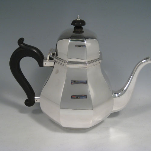    Sterling silver tea and coffee service, consisting of a coffee pot, teapot, sugar bow, and cream jug, having panelled bodies, wooden handles and finials, and hinged domed lids. Made by Garrards of London in 1957. Height of coffee pot 22 cms (8.75 inches), length of teapot 26 cms (10.75 inches). Total weight approx. 2,350g (75.8 troy ounces).